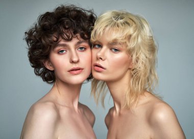 Studio portrait of two sensual young women with clean fresh face skin and perfect nude makeup