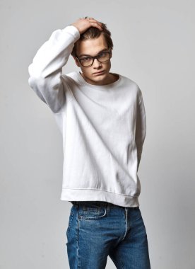 Saçına dokunan genç adamın portresi gri arka planda izole edilmiş.