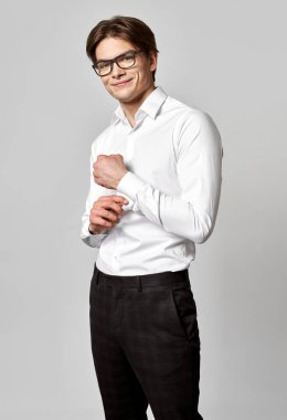 Genç mutlu adam beyaz klasik gömleğini ilikliyor.