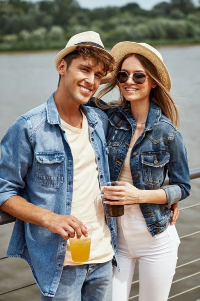 戴着太阳镜的年轻漂亮女人的画像戴着夏帽 和一个英俊的男人一起喝果汁 年轻夫妇在户外恋爱 — 图库照片
