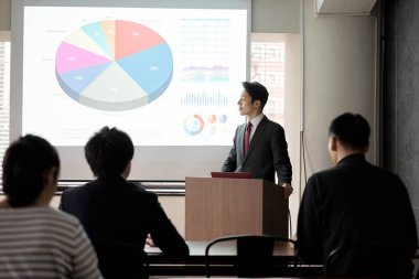 Asyalı işadamı konferansta sunum yapıyor.