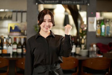 Asyalı bir kadın restoranda poz veriyor.