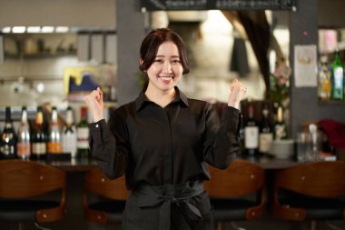 Asyalı bir kadın restoranda poz veriyor.