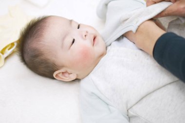 Asyalı baba bebek kıyafetleri değiştiriyor