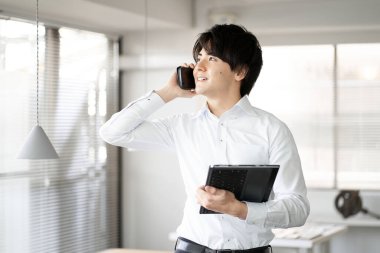 Asyalı adam ofiste telefon görüşmesi yapıyor.