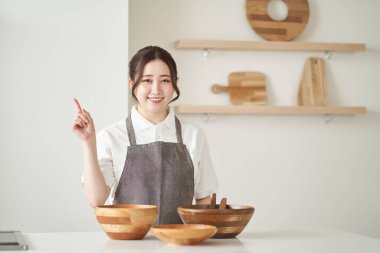 Asyalı kadın mutfağı işaret ediyor.