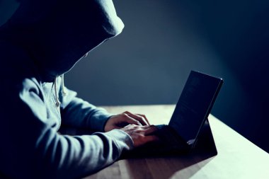 Erkek hacker dizüstü bilgisayarda kod yazıyor.