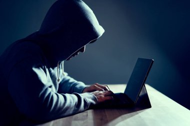 Erkek hacker dizüstü bilgisayarda kod yazıyor.
