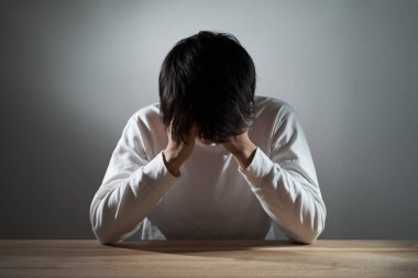 Asyalı adam karanlık bir odada depresyonda.