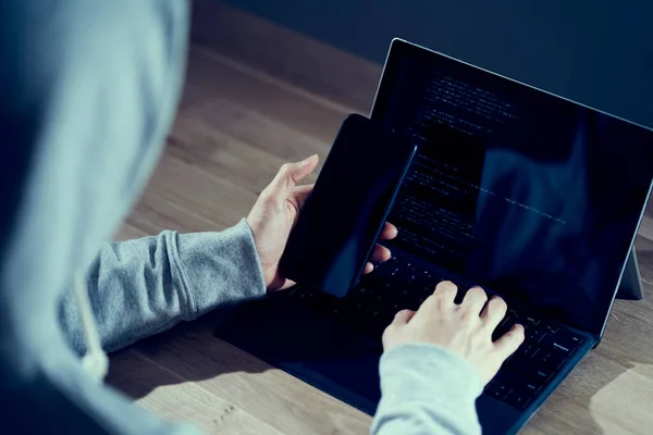 Erkek bir hacker akıllı telefondan operasyonu kontrol ediyor.