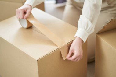 Asyalı kadın karton üzerine sakız bandı yapıştırıyor.