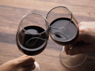 Bir adam ve bir kadın ellerinde şarapla kadeh kaldırıyor.