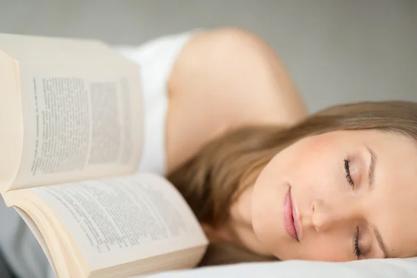 Affascinante femmina che si riposa e legge un libro sdraiato su un divano — Foto Stock