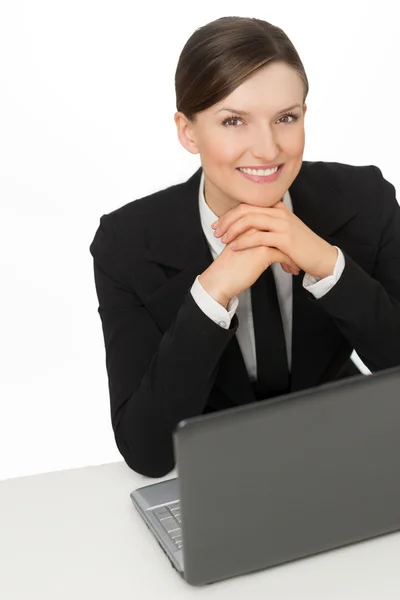 Mujer de negocios sonriendo con el ordenador portátil sentado cerca del escritorio —  Fotos de Stock