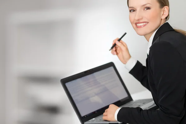 Business woman showing laptop screen and pen — Stock Photo, Image