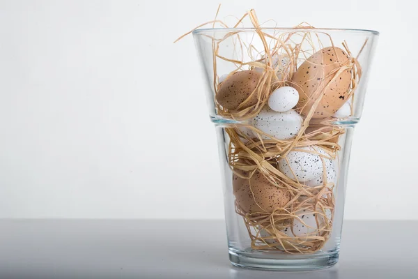 Пасхальные яйца в стеклянной вазе на столе — стоковое фото