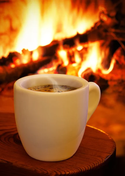 Uma xícara de café quente na frente da lareira — Fotografia de Stock