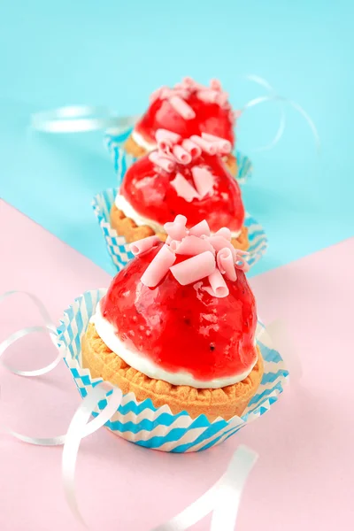 Three little cupcakes with cream and strawberry glaze — Stock Photo, Image