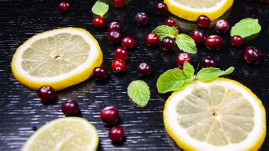 Siyah ahşap bir masada limon, kızılcık ve nane. Yakın plan.