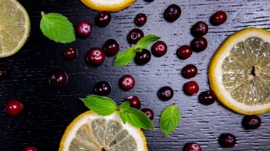 Siyah ahşap bir masada limon, kızılcık ve nane. Yakın plan.