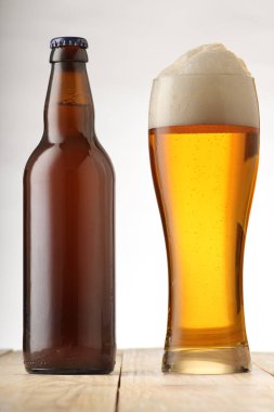 Beyaz arka planda dolu bir bardak bira şişesi.
