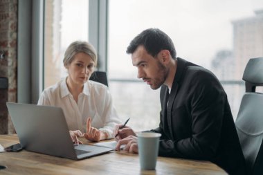 İş dünyasında takım çalışması. Erkek ve kadın ortaklar, iş arkadaşları kalkınma stratejisini, iş meselelerini, masa ve dizüstü bilgisayardaki yeni projenin özelliklerini tartışıyorlar.