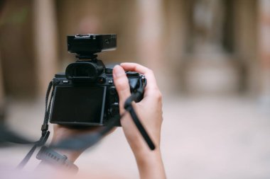 Profesyonel bir kameranın kadın ellerinde yakın plan çekimi. Kadın fotoğrafçı çekim yapıyor, odaklanıyor, kart arıyor, fotoğraf çekiyor.