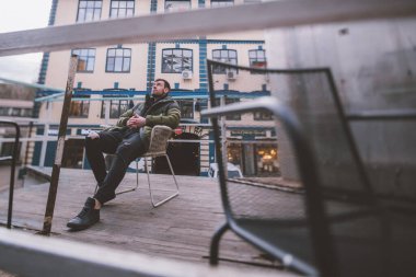 Modern bir şehrin kentsel sanat alanında modern bir adamın portresi. Genç yakışıklı bir adam yaratıcı bölgede alışılmadık yerlerde poz veriyor. Açık alanlarda aktif dinlenme kavramı