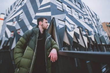 Modern bir geometrik mekanda şık giyinmiş genç bir adam. Modern insanın görüntüsü. Şehir caddesinde ceketli yakışıklı esmer bir adamın portresi..