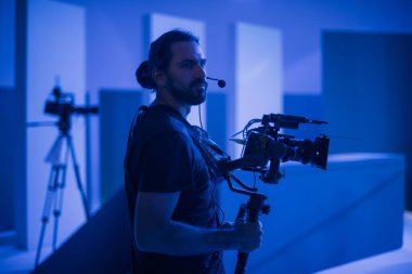 Görüntü yönetmeni elinde kamerayla sette. Bir film, ticari ya da televizyon dizisi çekmek için çalışan profesyonel bir videograf. İçerideki çekim süreci, stüdyo.