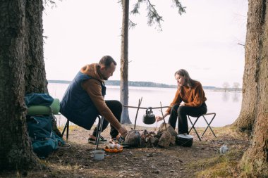 Evli bir çift gölün kıyısında çadırlı şekerlemeleri kızartıyor. Ormanda şenlik ateşiyle yürüyüş kampı. Kadın ve erkek, ateşin yanında sıcak içeceklerle sessizliğin tadını çıkarırlar.