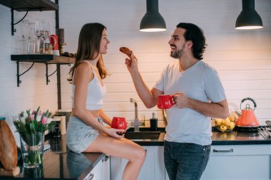 Sabahları evdeki mutfakta birbirini seven genç bir çift. Erkek ve kadın şık bir mutfakta eğlenceli bir kahvaltı yapıyorlar..