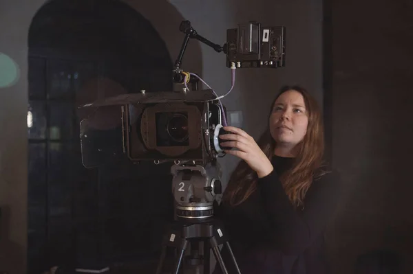 A young female director of photography at work behind a movie camera on a film set for a movie, commercial or broadcast. Modern photography technology.