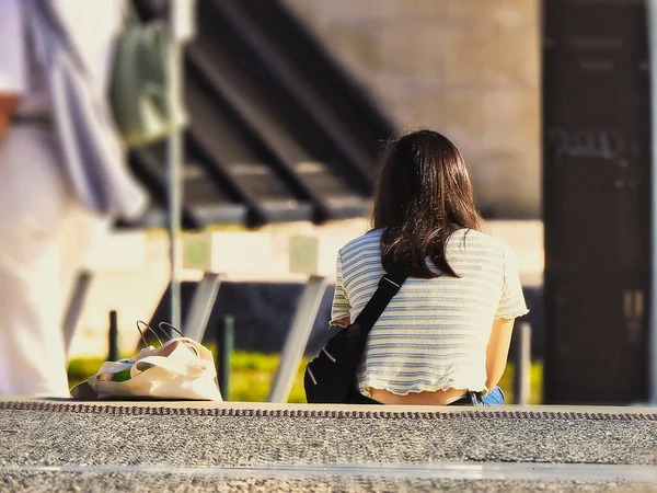 ベンチに座って携帯電話の相談をしている若い女性 — ストック写真