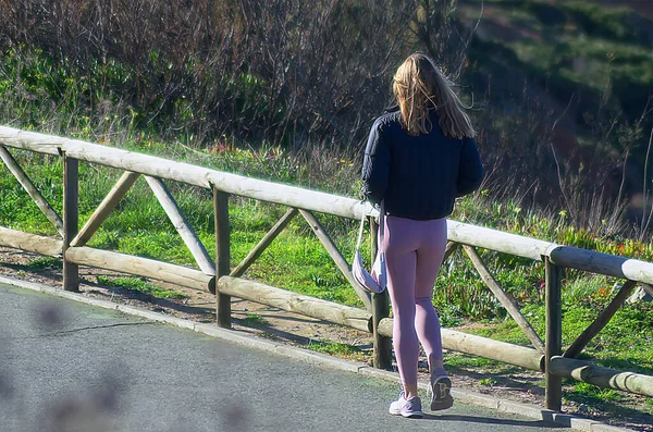 若いですブロンド女性でピンクタイツ歩行によって木のフェンス — ストック写真