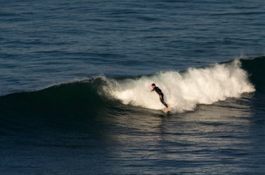 Atlantik Okyanusu 'ndaki dalganın tepesinde bir sörfçü