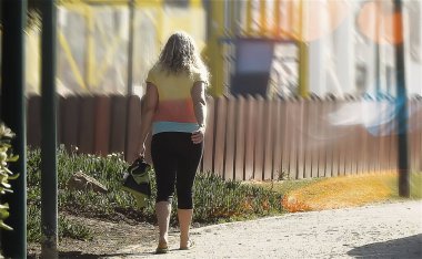 Bermuda şortlu sarışın kadın kaldırımda yürüyor.