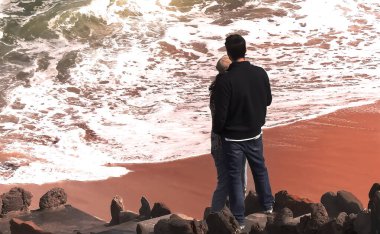 Okyanusun kıyısındaki insanlar dalgalara hayran.