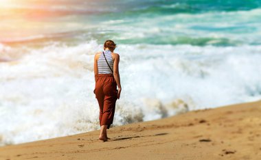Güneşli bir sabahta kumsalda tek başıma yürüyorum.