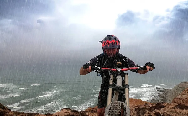 Siyah Kıyafetli Bisikletçi Okyanusun Yakınındaki Yağmura Yakalandı — Stok fotoğraf