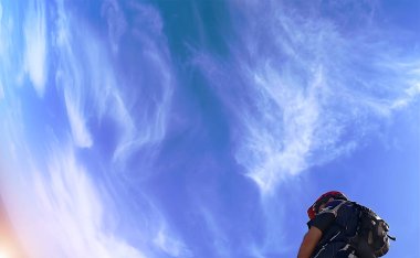 Güzel bulutlu mavi bir gökyüzü ve köşede bir bisikletçi.