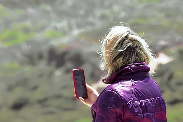 Woman in purple jacket taking pictures with mobile phone