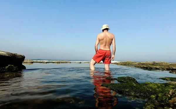 Man Red Shorts His Feet Ocean Rocks — Photo