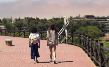 Two young women walking on a sidewalk