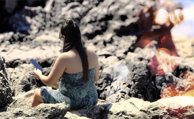 Woman sitting on rocks with mobile phone