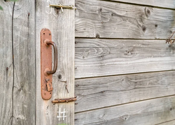 Zardzewiała klamka i dwa zatrzaski na drewnianej stodole lub drzwiach toaletowych, na wsi. Przestrzeń kopiowania. — Zdjęcie stockowe