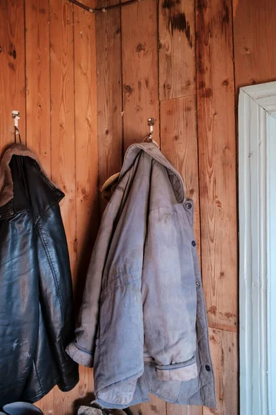 Теплые куртки для работы в саду висят на деревянной стене в загородном доме. — стоковое фото