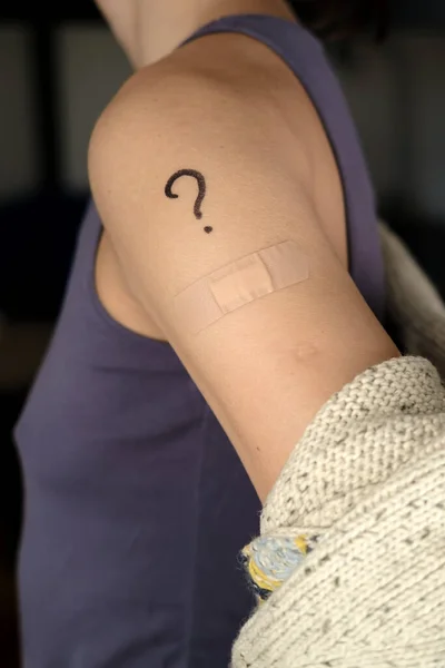 Umărul feminin cu semne de întrebare trase și bandaj după vaccinarea covid-19. Conceptul de selecție a vaccinurilor. — Fotografie, imagine de stoc
