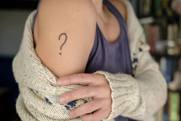 Женское плечо с нарисованным вопросительным знаком. Концепция неопределенности, следует ли вакцинировать против ковида-19 и какую вакцину выбрать. — стоковое фото