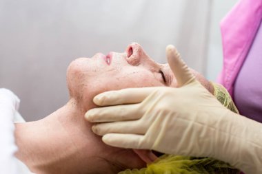 Güzellik uzmanı, masaj hareketleriyle kadının yüzünü temizliyor.. 